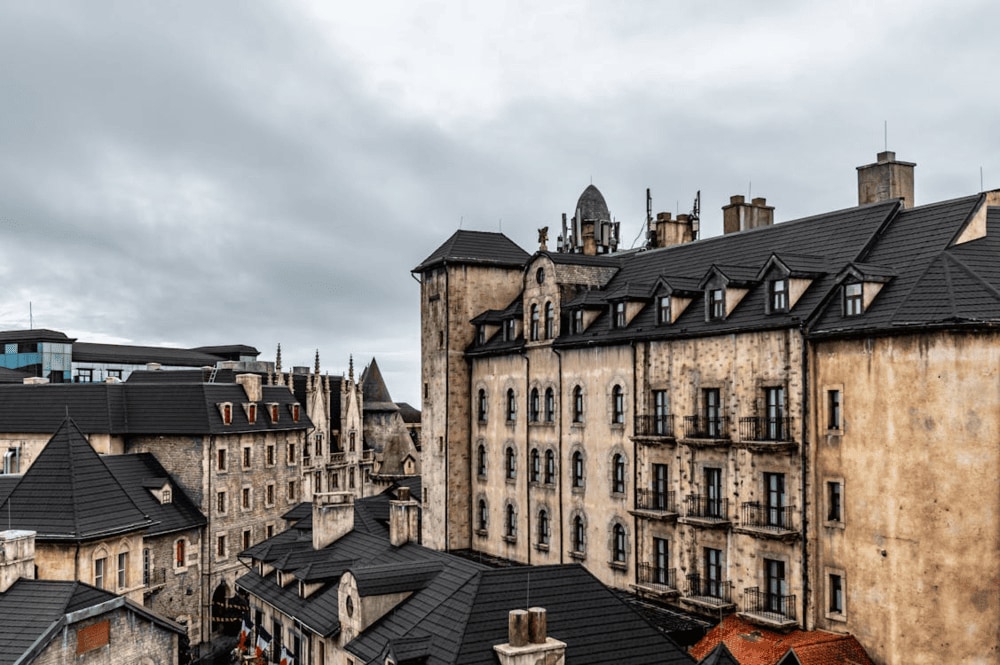 The charming French Village, bathed in the morning sunlight, is surrounded by a vibrant garden of colorful flowers (Source: Pexels)