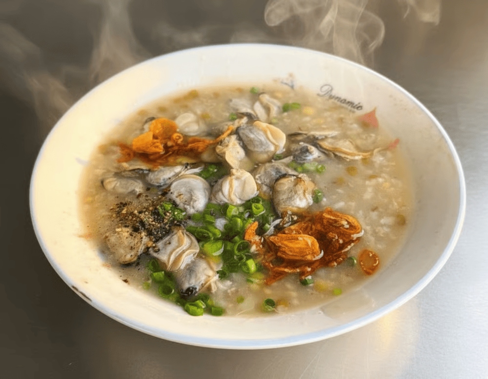 The fresh herbs, crispy shallots, and a hint of black pepper add layers of flavor, making each spoonful of clam porridge a delightful experience
