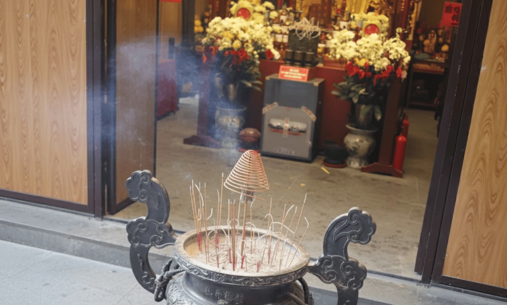 A grand incense burner (Lu huong) stands at the temple entrance, welcoming devotees